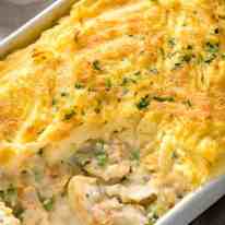 Close up of Fish Pie in white baking dish showing creamy filling with fish flakes