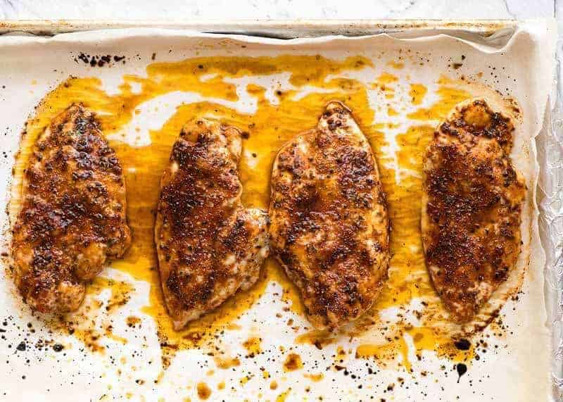 Overhead photo of juicy baked chicken breast on a tray, fresh out of the oven