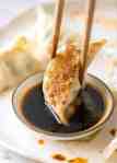 Potsticker being dipped in a small bowl with soy sauce and chilli oil