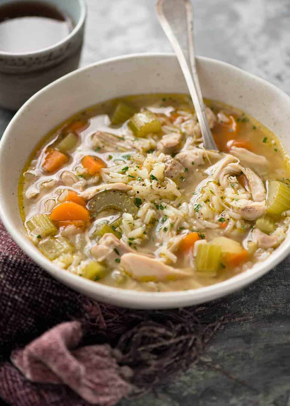 Easy chicken and rice soup in a rustic beige bowl, ready to be eaten.