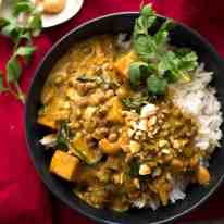 Coconut Curry with Lentils & Pumpkin served over rice in a small black bowl, ready to be eaten.