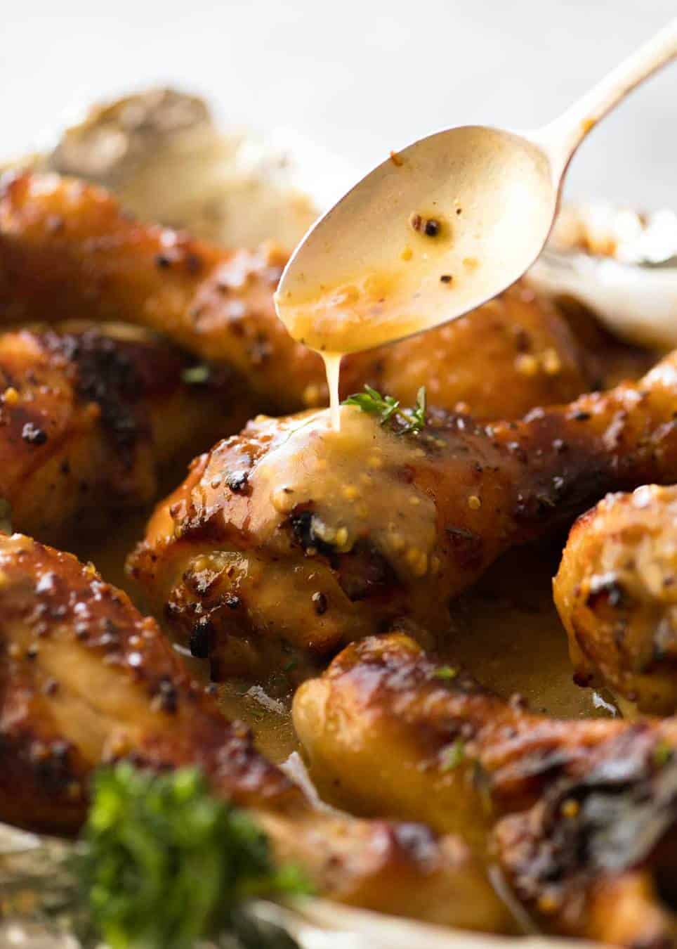 Close up of Honey Mustard sauce being drizzled over Baked Chicken Drumsticks