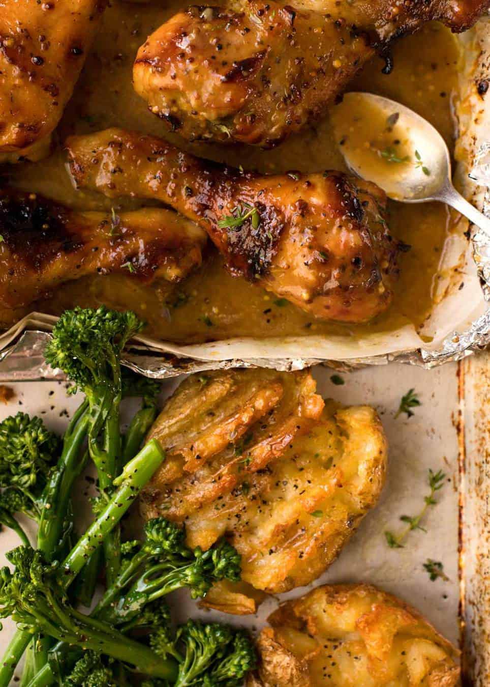 Overhead photo of easy chicken dinner - Honey Mustard Baked Chicken Drumsticks with Smashed Potatoes on a silver tray with a side of steamed broccolini