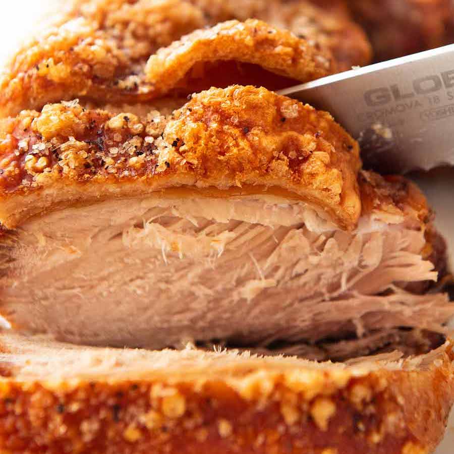 Close up slicing perfect pork roast with crispy crackling