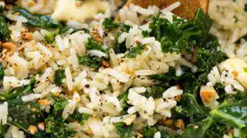 Close up of Garlic Butter Rice with Kale recipe in a pot with a wooden spoon, fresh off the stove ready to be served.