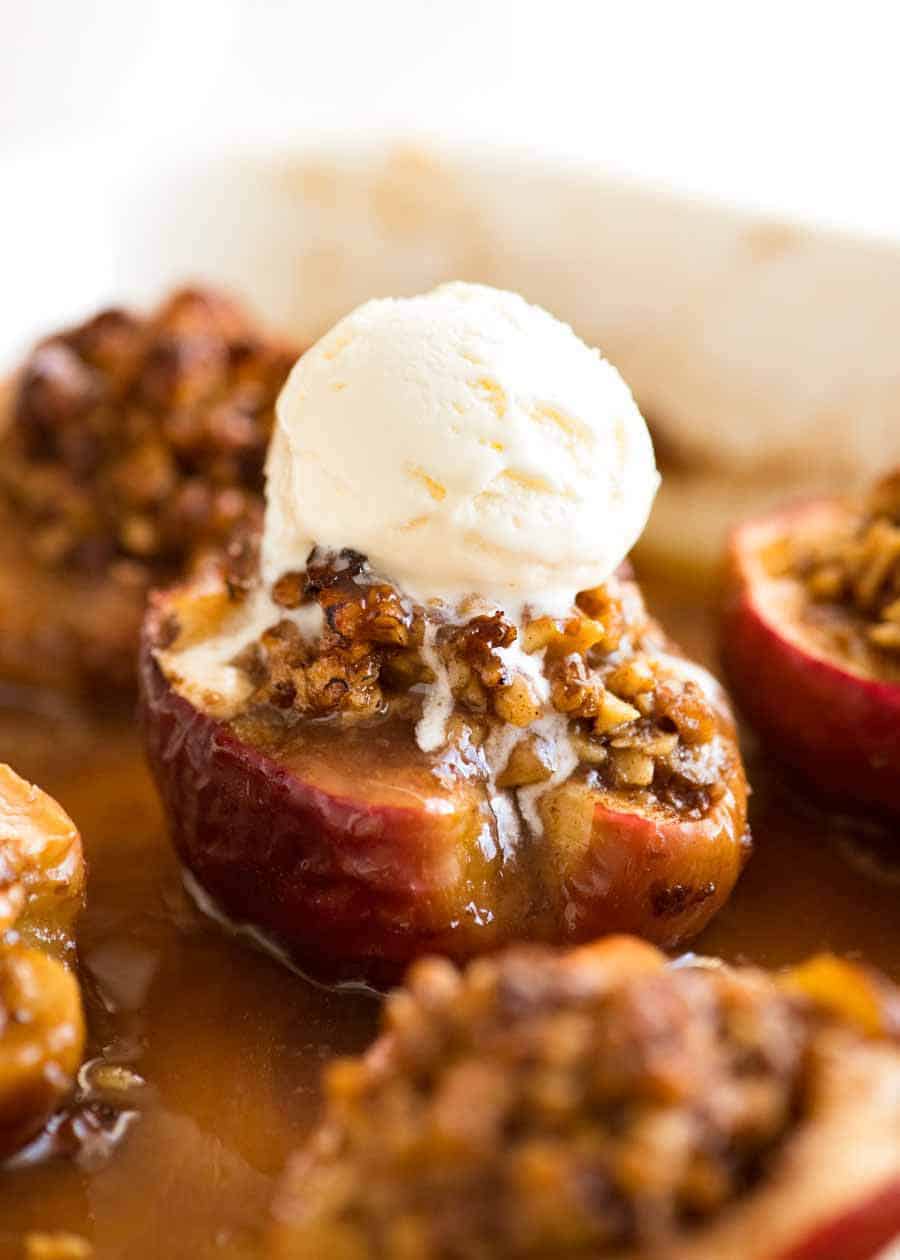 Close up of Caramel Self Saucing Baked Apples with ice cream on top in a baking dish, fresh out of the oven.