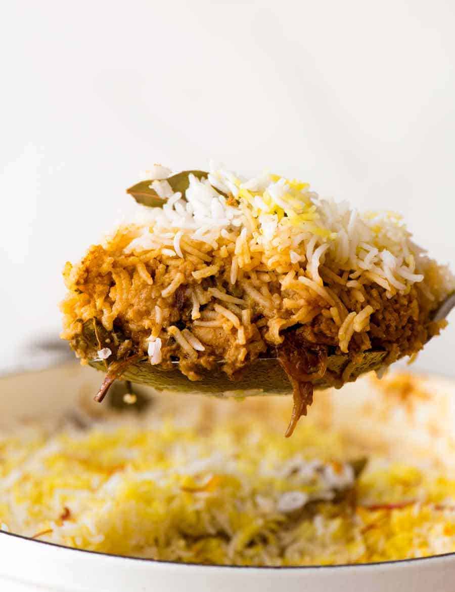 Serving Chicken Biryani from a white pot, showing the chicken curry and rice layers