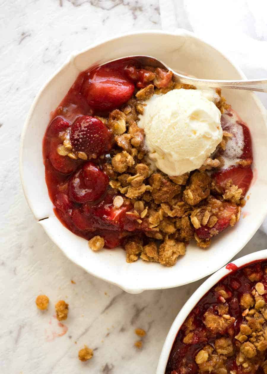 Overhead photo of Strawberry Crumble with vanilla ice cream in a rustic white bowl, ready to be eaten