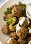 Close up of Falafels in a bowl drizzled with tahini sauce