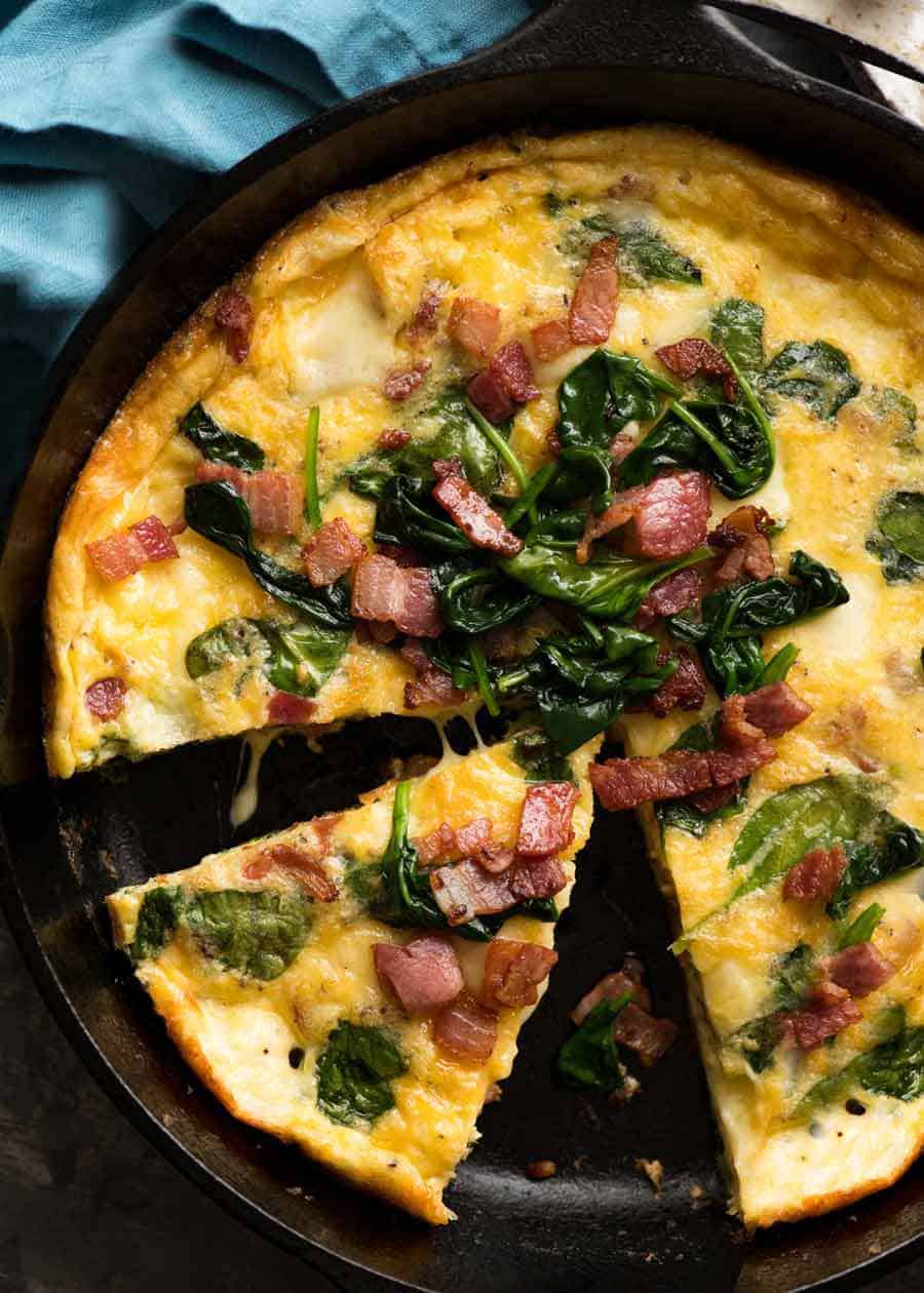 Overhead photo of Frittata with Bacon and Spinach in a black skillet, fresh out of the oven ready to be served