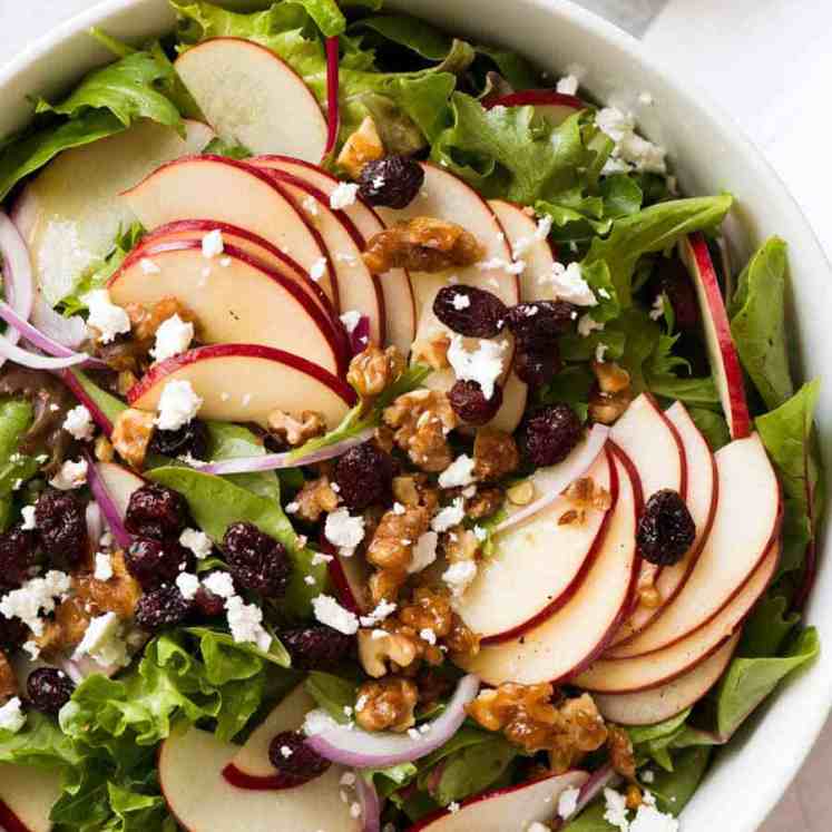 Overhead photo of Apple Salad with Candied Walnuts and Cranberries with vinaigrette dressing on the side