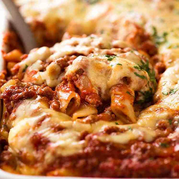 Scooping up Baked Ziti from baking dish