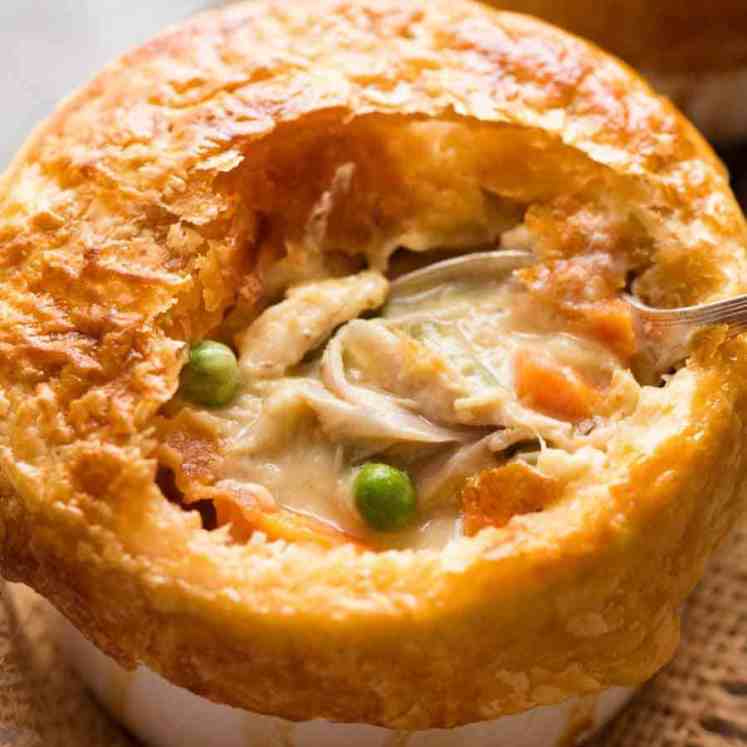 Close up of Chicken Pot Pie in a ramekin with puff pastry topping, made from scratch with uncooked chicken.