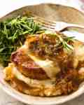 French Onion Smothered Pork Chops on mashed potato with a side of sautéed snow pea sprouts