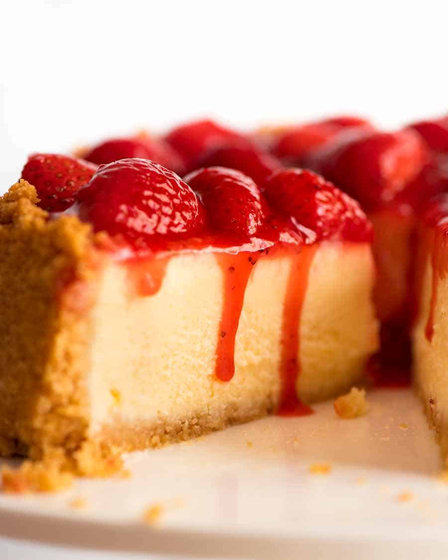 Close up of slice of Strawberry Cheesecake with Strawberry Sauce dripping down the side
