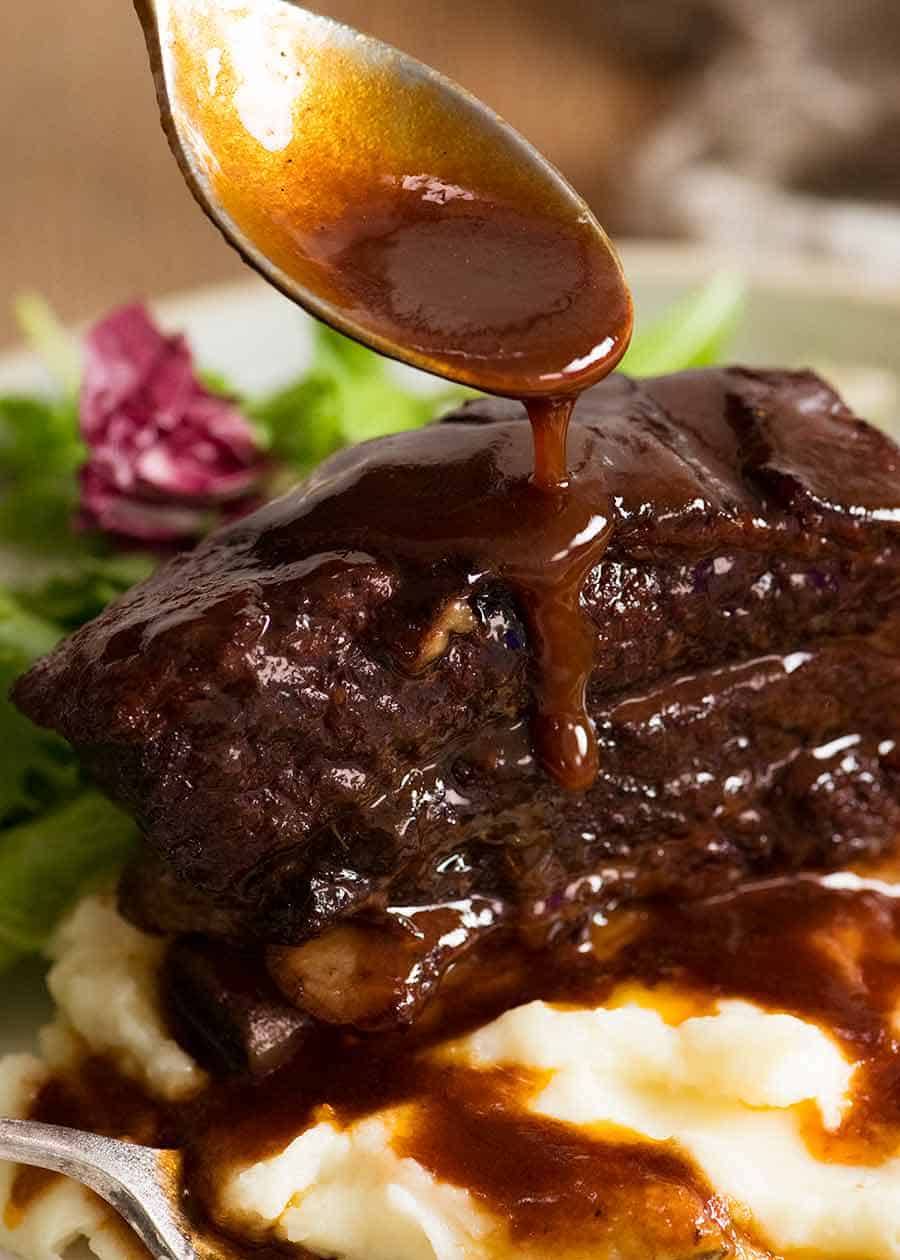Spoon drizzling Red Wine Sauce over Slow Braised Beef Short Ribs