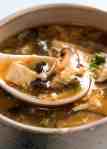 Close up of Chinese spoon scooping up Hot and Sour Soup from bowl