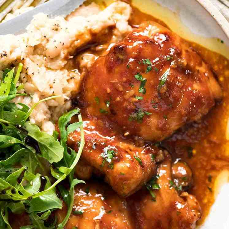 Overhead photo of Sticky Baked Chicken Thighs on a plate with a side of mashed white beans and rocket parmesan salad