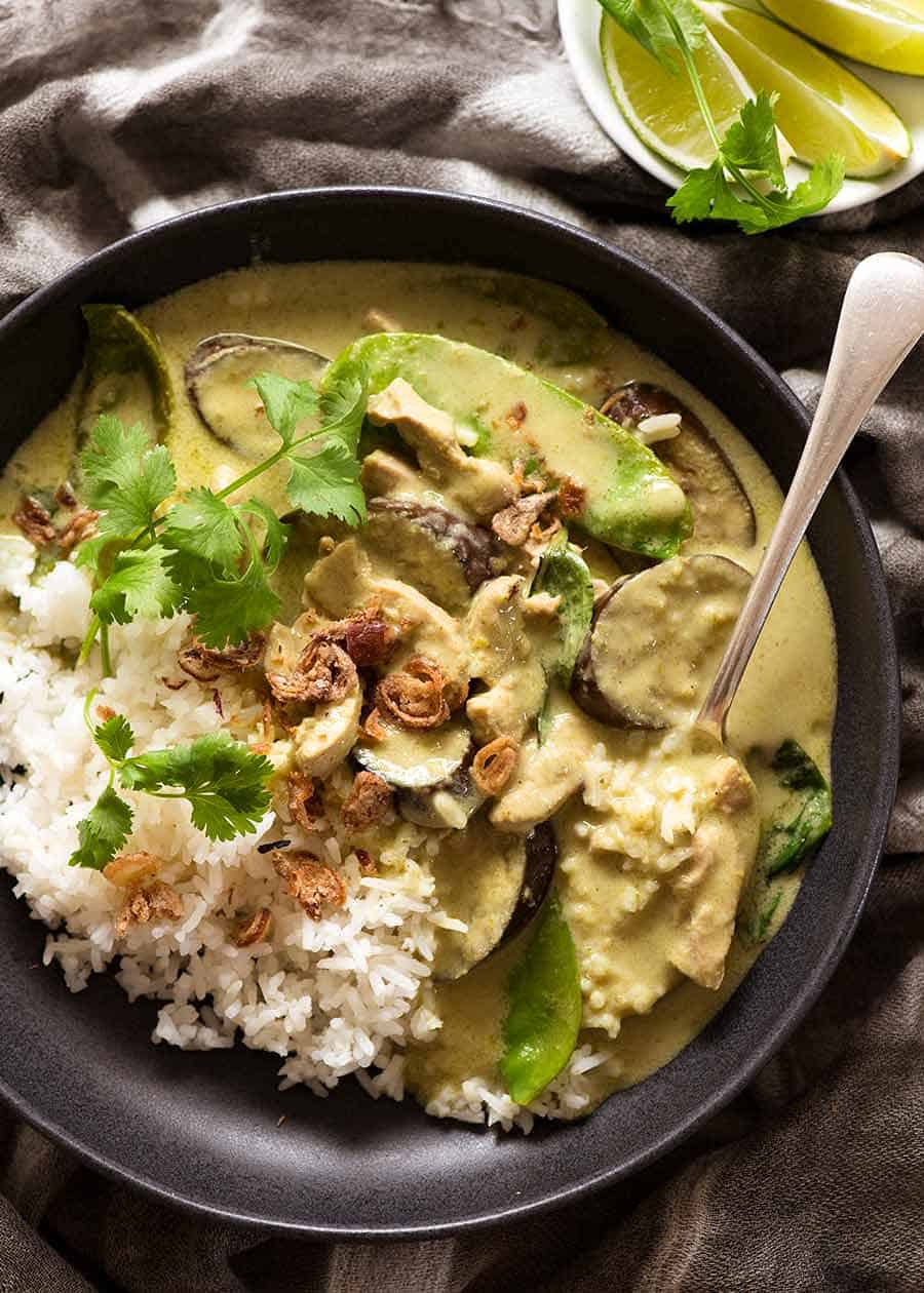 Thai Green Curry served over rice in a black bowl with lime wedges on the side, ready to be eaten