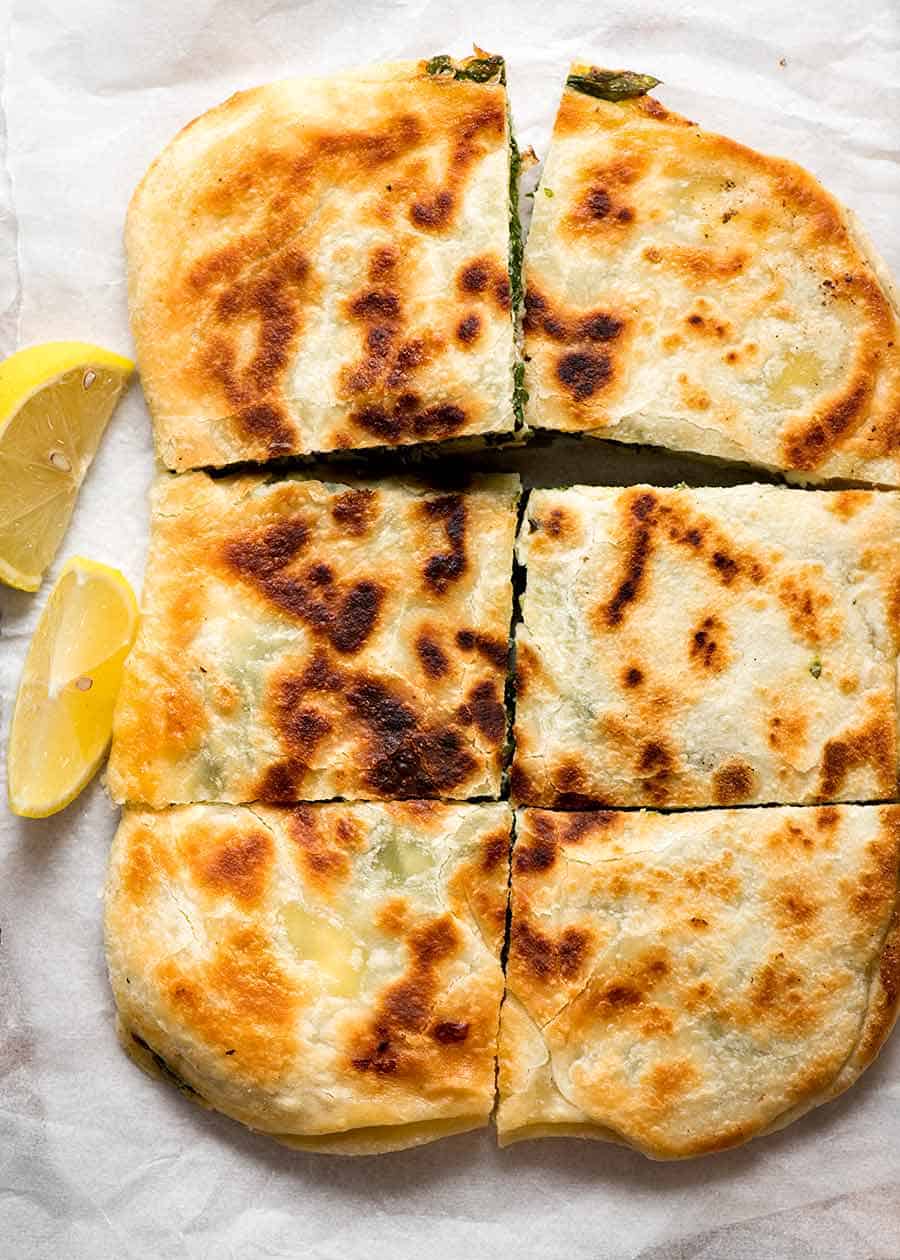 Overhead photo of Spinach and Feta Gozleme cut into 6 pieces served with lemon wedges on the side