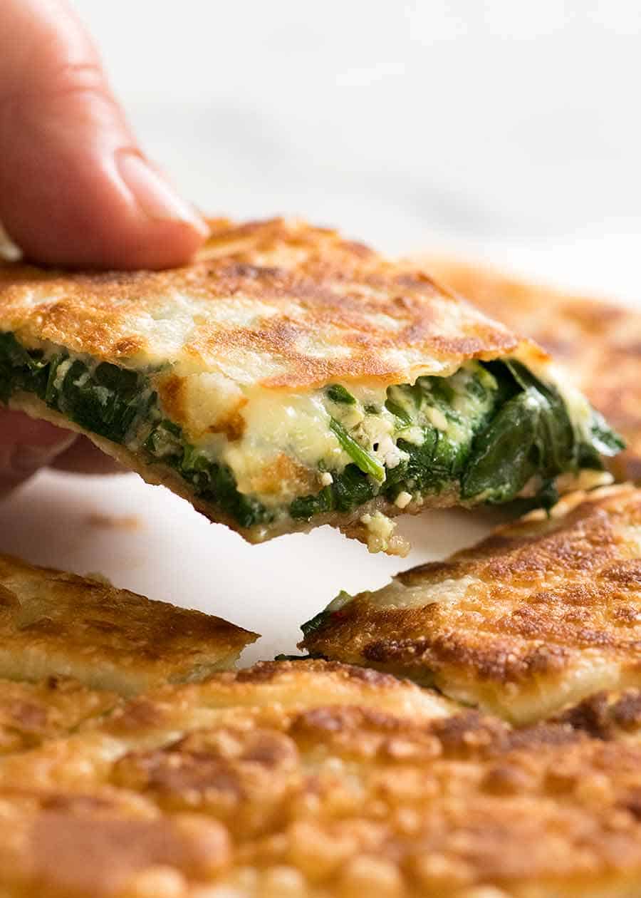Hand picking up piece of Spinach and Feta Gozleme