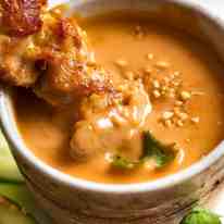 Close up of Thai Chicken Satay being dipped into Thai Peanut Sauce