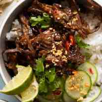 Overhead photo of Caramelised Vietnamese Shredded Beef served over rice with lime wedges, cucumber, chilli and peanuts
