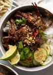 Overhead photo of Caramelised Vietnamese Shredded Beef served over rice with lime wedges, cucumber, chilli and peanuts