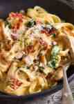 Close up of chicken pasta with creamy alfredo sauce, sun dried tomato, spinach and bacon