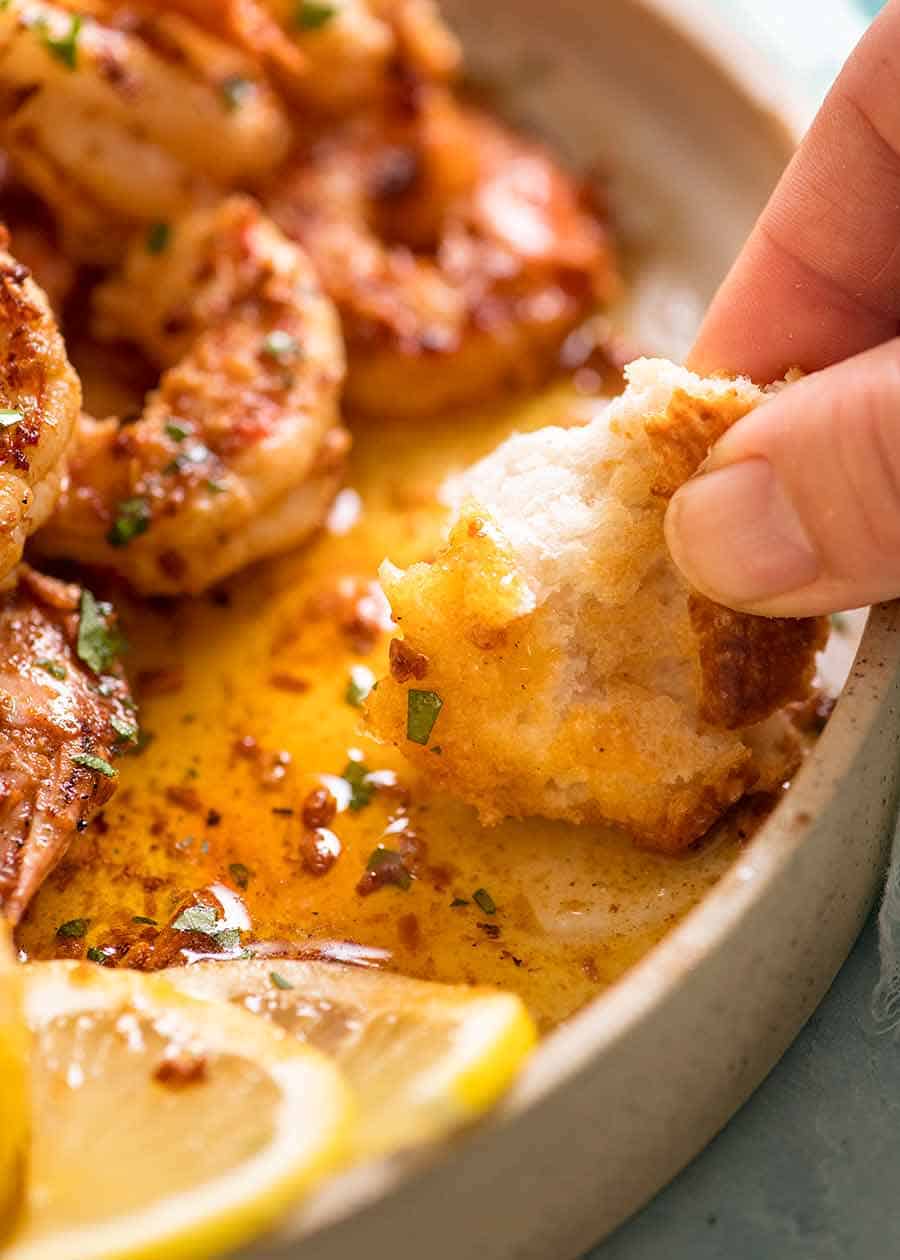 Bread being dipped into Lemon Garlic Butter Sauce served with Grilled Shrimp