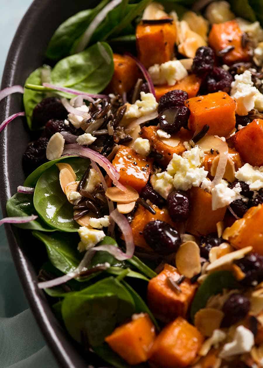 Close up of sweet potato salad with baby spinach, feta, almonds, red onion, wild rice drizzled with a Honey Lemon Dressing