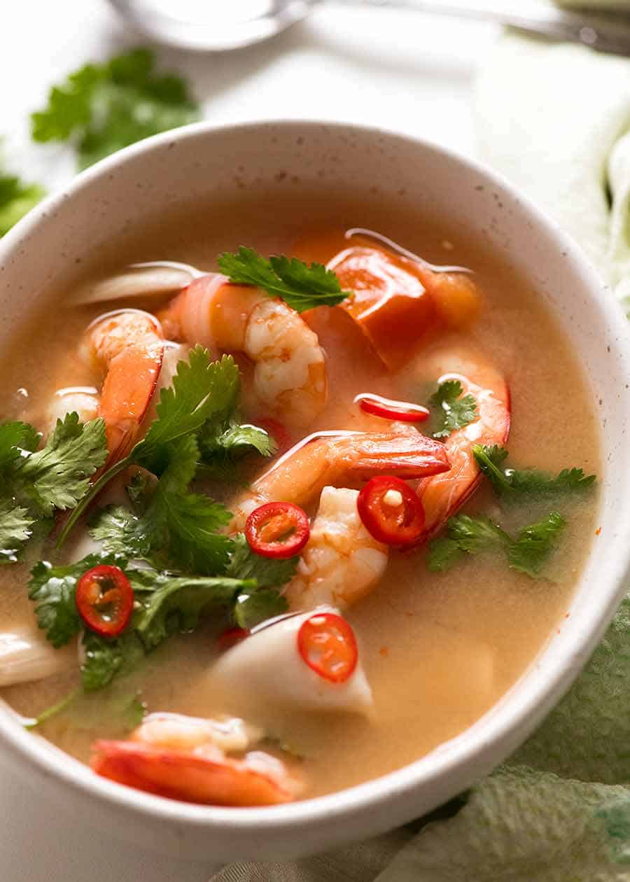 Rustic white bowl with Thai Soup - Tom Yum soup - ready to be eaten