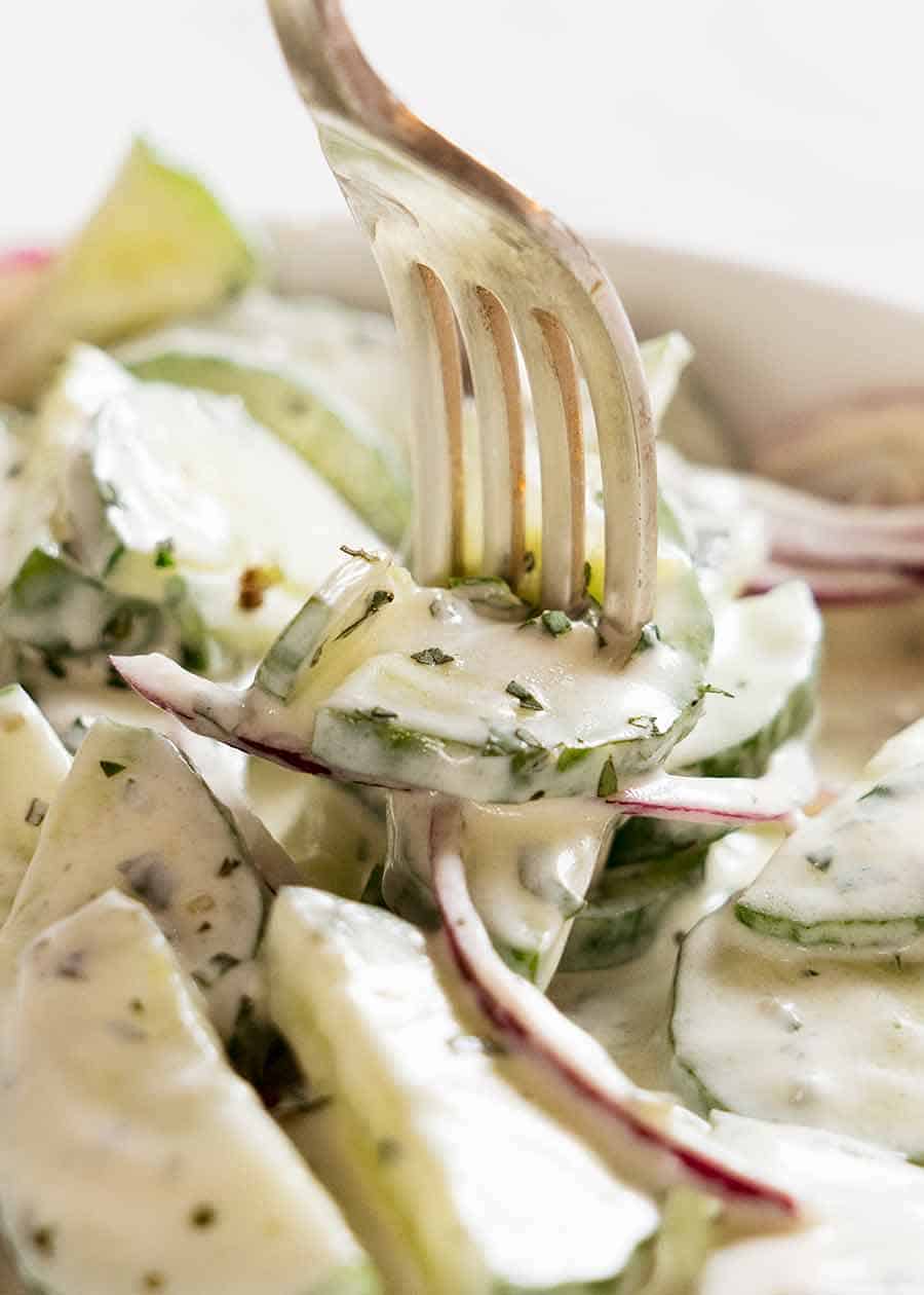 Close up of fork picking up Cucumber Salad with Lemon Mint Yogurt Dressing