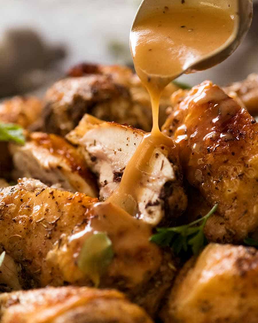 Close up drizzling gravy over crispy roast chicken