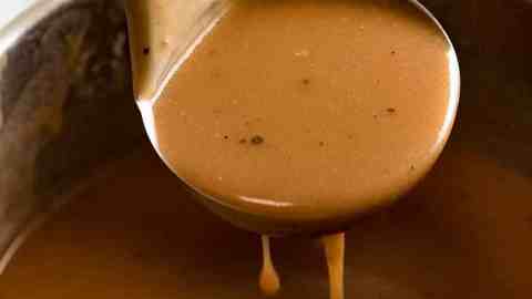 Ladle scooping up gravy from saucepan