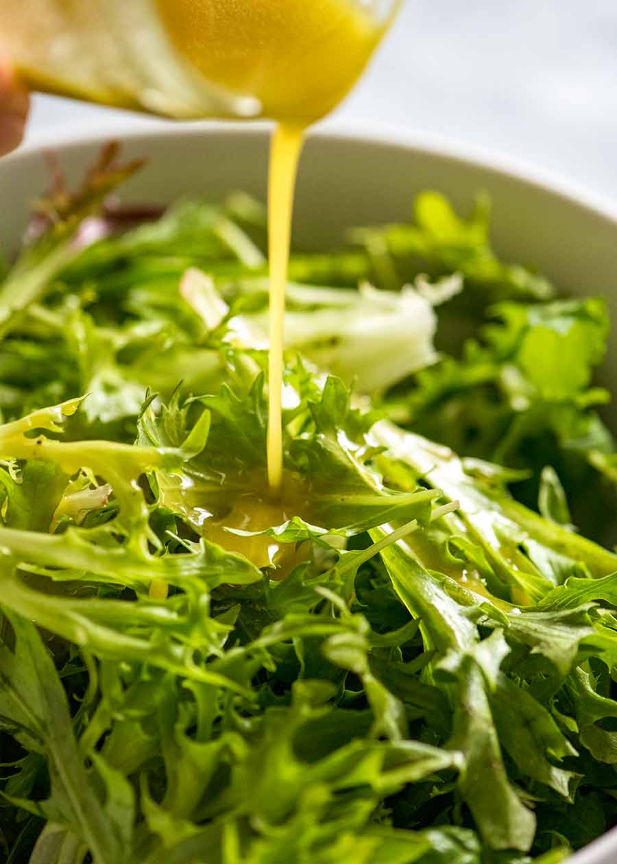 Pouring salad dressing over leafy salad