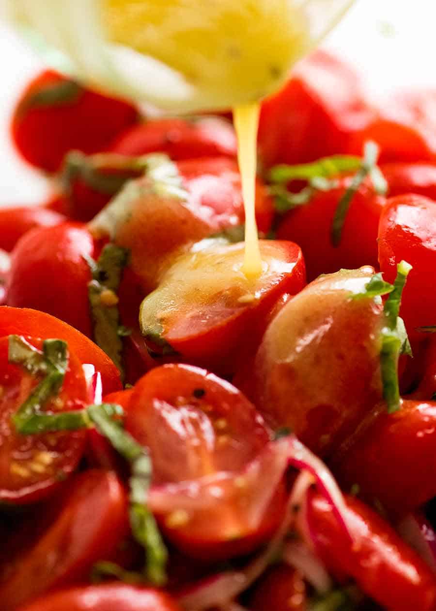 Pouring vinaigrette over Tomato Salad