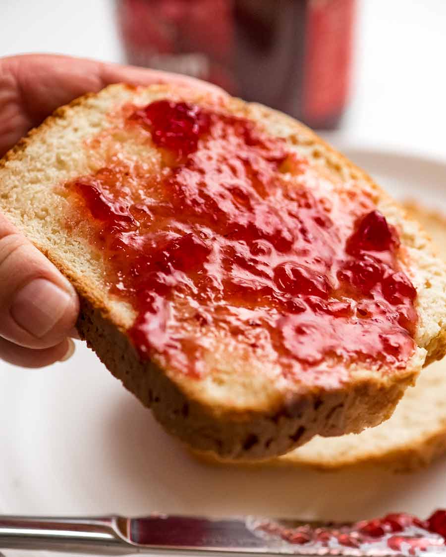 Close up of hand holding slice of No Yeast Sandwich bread with jam