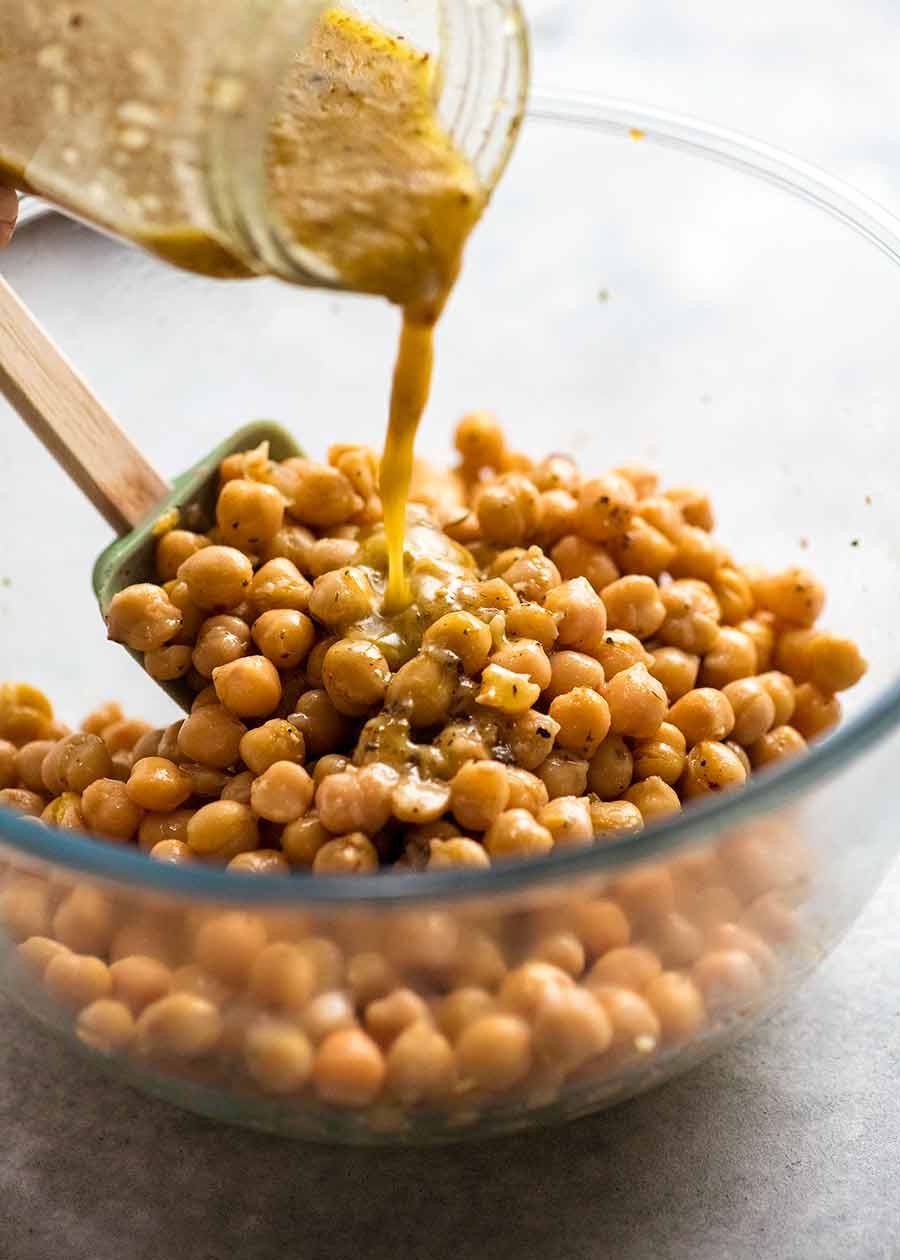 Pouring dressing over chickpeas to marinate them