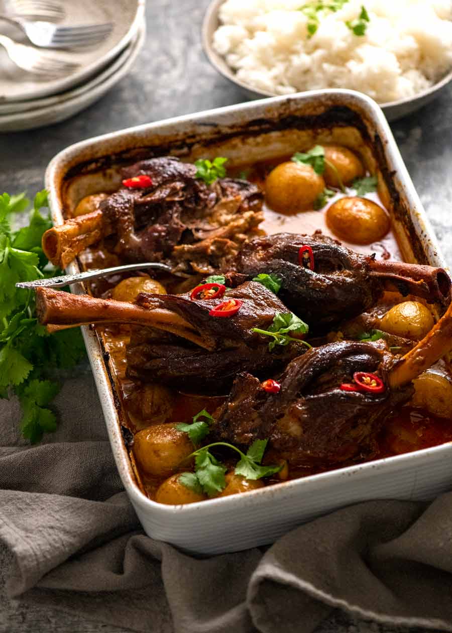 Slow Roasted Lamb Shanks in Massaman Curry in a white baking dish, ready to be served