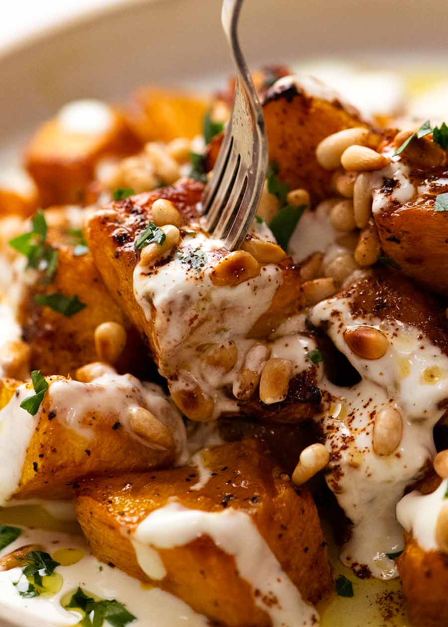 Fork picking up piece of Roast Pumpkin with Yogurt Sauce and Pine Nuts