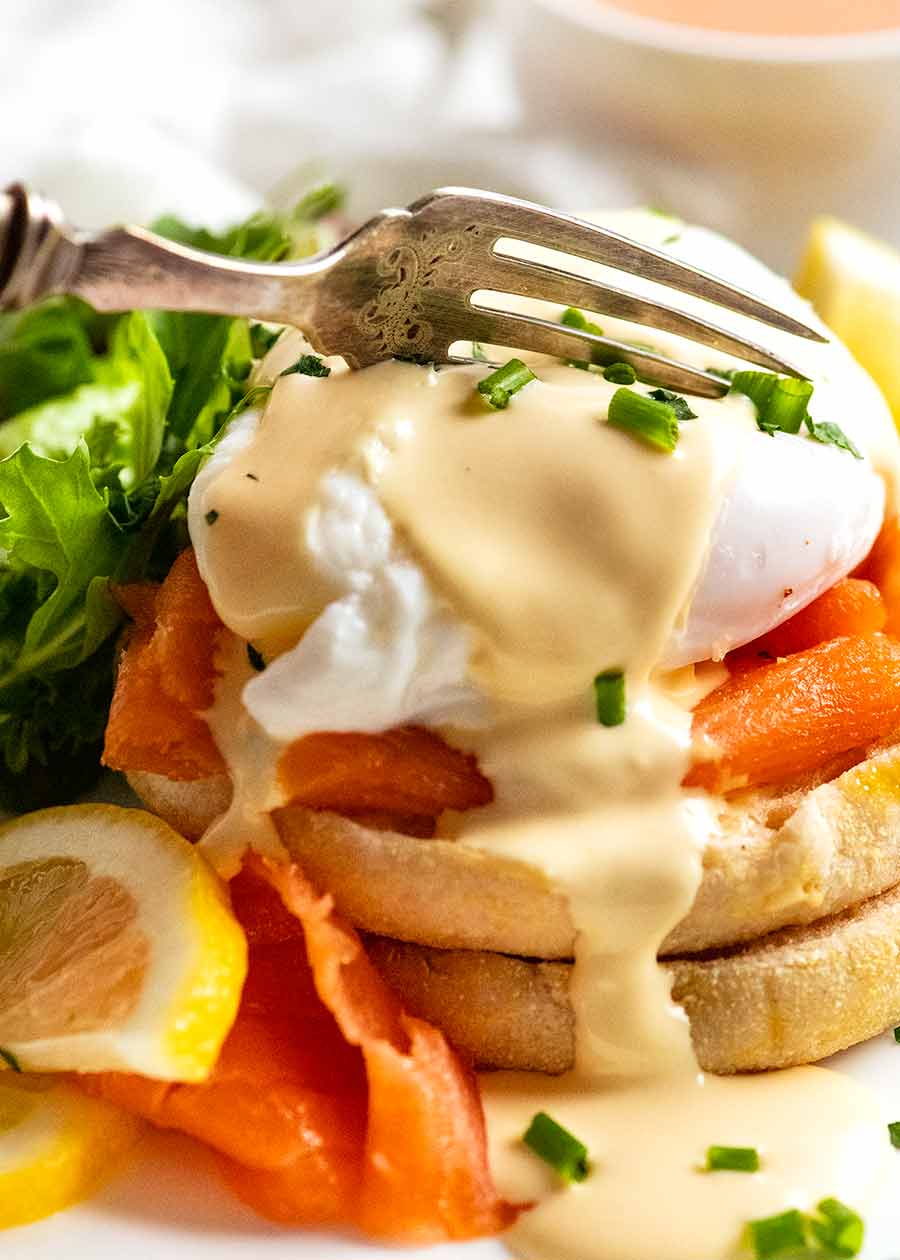 Fork cutting into Eggs Benedict with smoked salmon