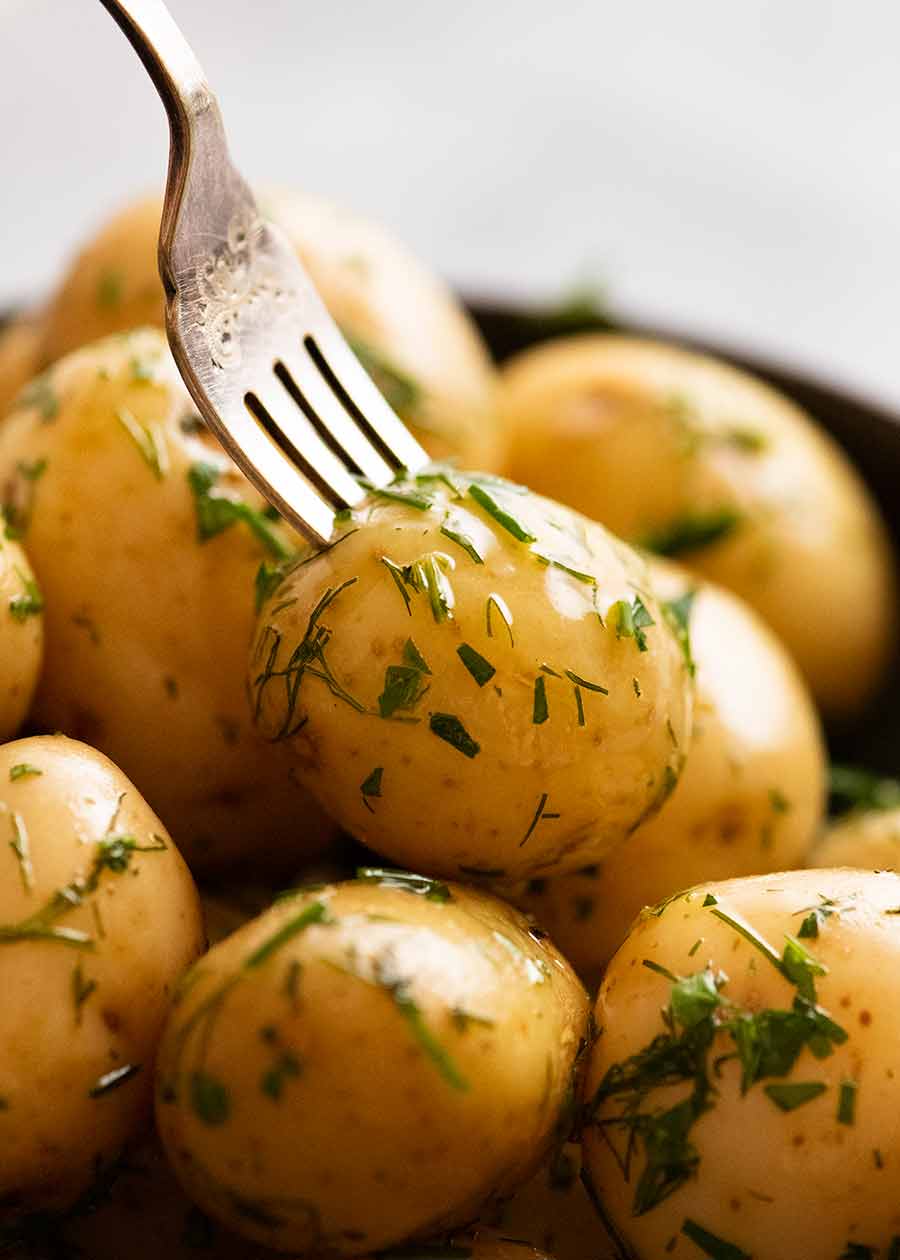 Fork picking up baby potatoes with butter