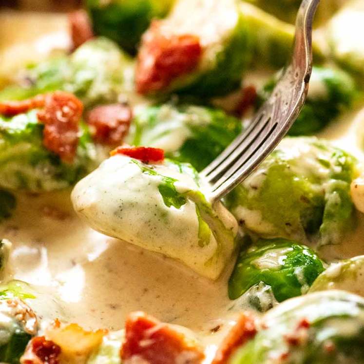 Fork picking up sautéed Brussels sprouts in a creamy sauce