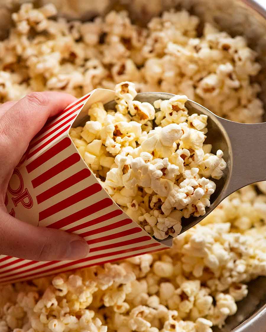 Scooping Slightly sweet and salty butter popcorn into popcorn holder