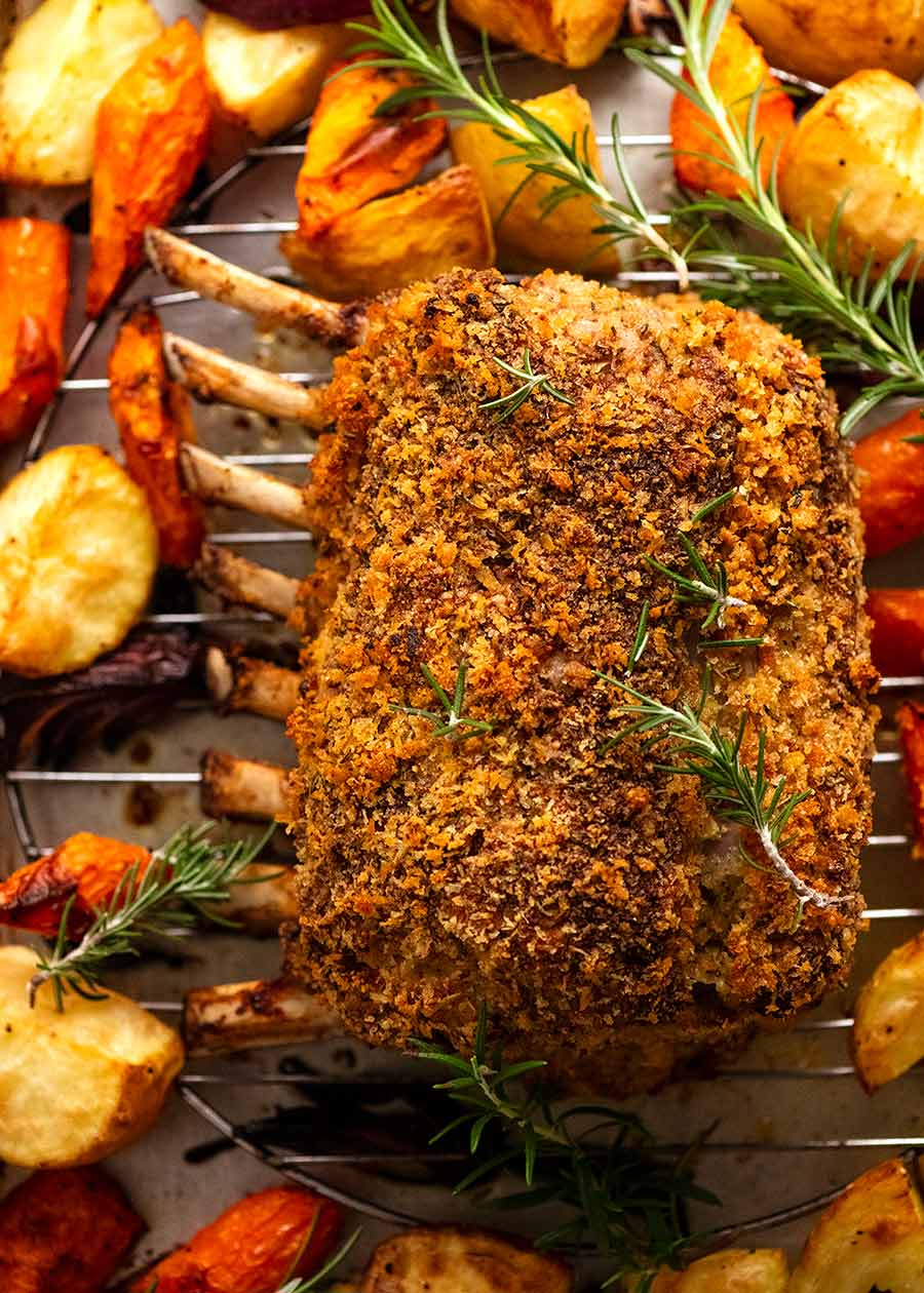 Rosemary Crumbed Rack of Lamb on a tray, fresh out of the oven, with roasted vegetables