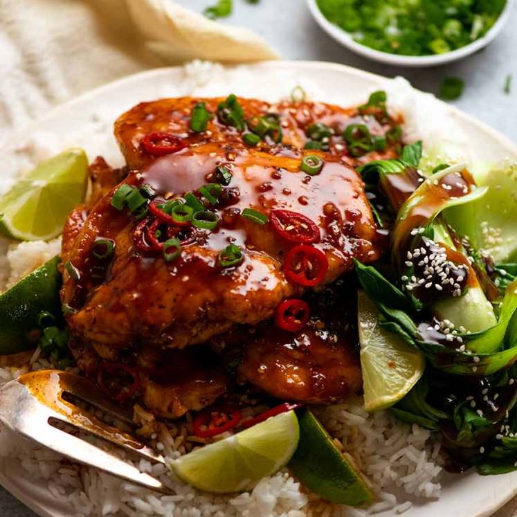 Pile of Asian Chilli Chicken served over rice with steamed asian greens on the side