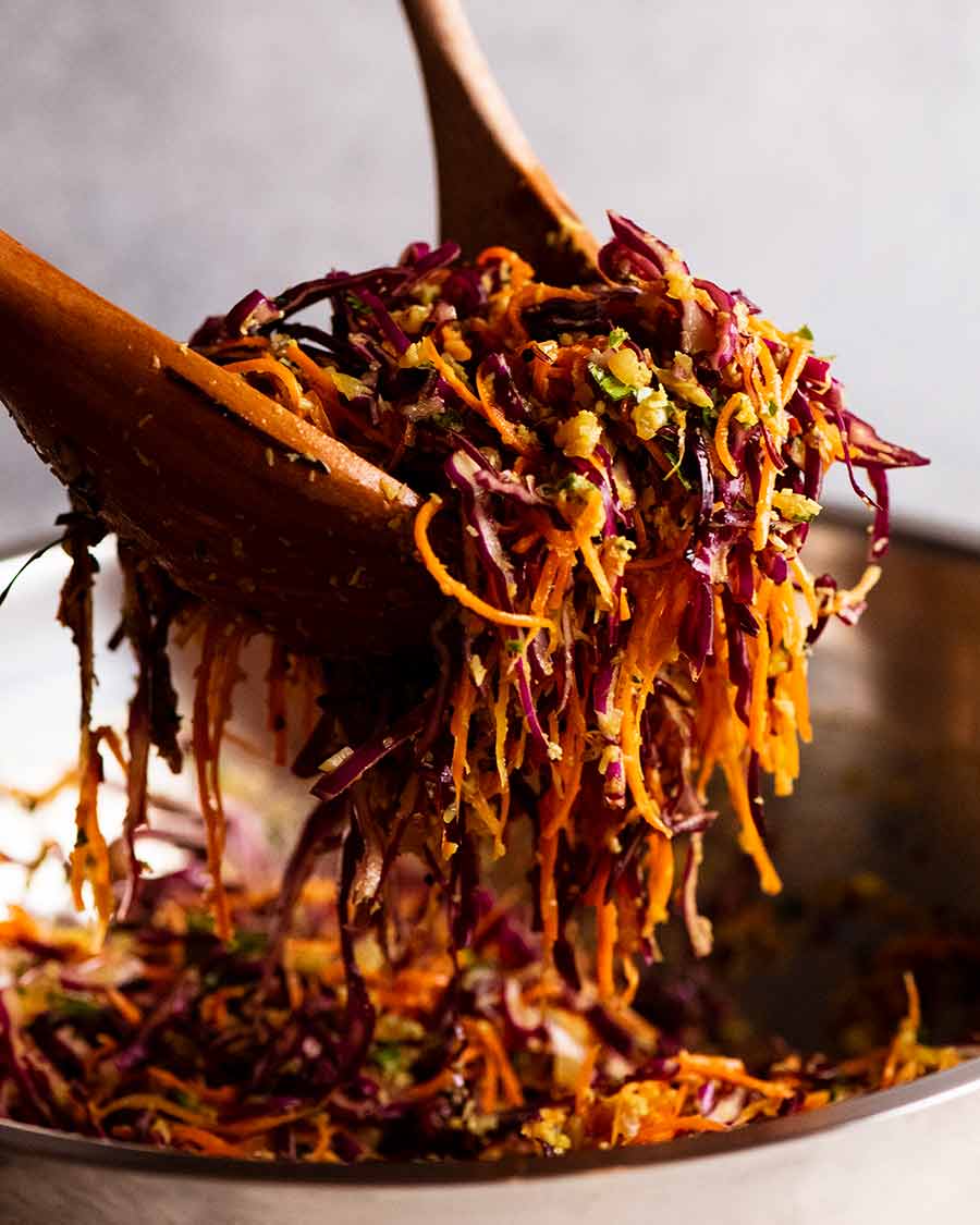 Wooden spoons tossing Cabbage and Carrot Thoran-style salad (Indian Salad)