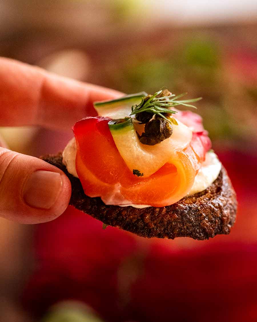 Close up photo of Beetroot Cured Salmon on crispy bead with Horseradish Cream Sauce, Fried Capers and fresh dill