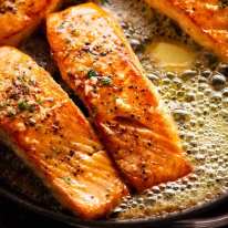 Garlic Butter Salmon in a skillet surrounded by foaming garlic butter